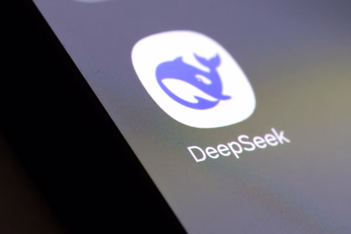 App icon on screen: blue whale logo with "DeepSeek" text beneath on a digital display. Dark edges suggest a close-up view.